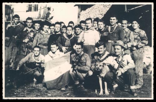 Anonimo, Borgata Molè (Chianocco). In posa, con armi, bandiera e mascotte, i partigiani del Distaccamento Aldo Rossero della 42ª Brigata Garibaldi., 1945 circa, CC BY-NC-SA