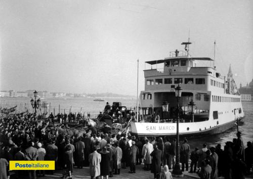 1962, Venezia. Una delle antiche diligenze postali ricostruita per le celebrazioni rievocative del primo centenario delle Poste Italiane, partita da Muggia e diretta a Roma, percorre una parte del suo viaggio a bordo della nave traghetto San Marco e sbarca al molo del Bacino San Marco sotto gli sguardi ammirati del pubblico, CC BY-NC-ND