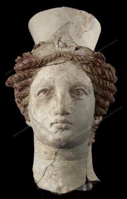 Archivio fotografico Museo archeologico reg. Paolo Orsi SR - Gallitto G., Testa pertinente a un busto femminile - da Siracusa - fine IV, inizi III sec. a.C.  Questa testa in terracotta policroma, caratterizzata dal tipico copricapo, fa parte di un gruppo di tre busti dedicati a uno dei culti più antichi a Siracusa e dei più praticati in tutta la Sicilia, il culto di Demetra e Persefone, madre e figlia, diffuso tra il V e il III sec. a.C.  I busti raffigurano Persefone, detta anche Kore, cioè fanciulla. L'acconciatura e i monili ricercati esprimono il fascino e la grazia giovanile. L'immagine di Persefone, rapita dal dio degli inferi, Ade, destinata a una vita a metà fra la terra e il regno dei morti, impersona la fanciullezza e il suo stato verginale, quasi in procinto di convogliare a nozze, che non verranno mai., fotografia still life digitale, CC BY-NC-ND