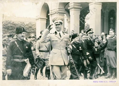 Corradino Toso, Via Battistero, Biella, cittadini, miliziani e membri dell’esercito, salutano il passaggio di Umberto di Savoia Principe di Piemonte, 17/06/1936, CC BY-NC-ND