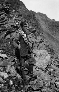 La guida alpina Benjamin Vallazza, ritratto a figura intera, ripresa all'aperto con corda e piccozza in zona rocciosa. ALPI SARENTINE ARCHIVIO FOTOGRAFICO ERICH PLANINSCHEK, n. 460, CC BY-NC-SA