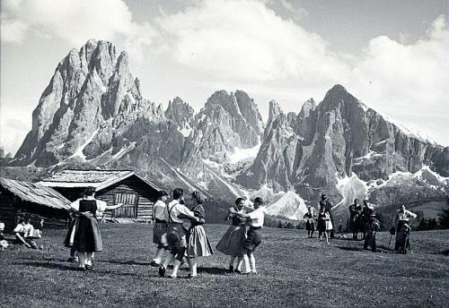 Alcune coppie di ballo sul prato di una malga con il Sassolungo ed il Sassopiatto sullo sfondo. CASTELROTTO, Alpe di Siusi, 29.06.1941 COLLEZIONE ROMEO SOMMAVILLA, n. 142, CC BY-SA