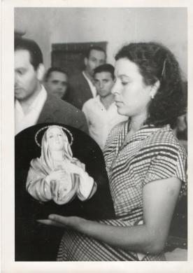 Saraceno, Giuseppe, La Signora Antonina Giusto con in mano il quadretto miracoloso, fotografata dalla finestra della sua camera da letto dal fotografo Saraceno, 08/1953, stampa su carta gelatina ai sali d'argento, CC BY-NC-ND