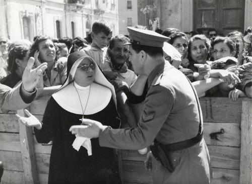 Meldolesi, Ivo, Una  religiosa discute con un  agente della polizia, addetto all'ordine pubblico durante i giorni della Lacrimazione.  Alle loro spalle la folla in devozione., 08/1953, stampa su carta gelatina ai sali d'argento, CC BY-NC-ND