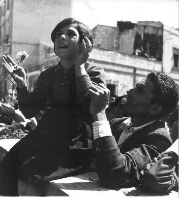 Meldolesi, Ivo, Una bambina seduta sul muretto di Casa Lucca, sorretta dal padre, con in mano un fiore, implora la Madonna, 08/1953, stampa su carta gelatina ai sali d'argento, CC BY-NC-ND